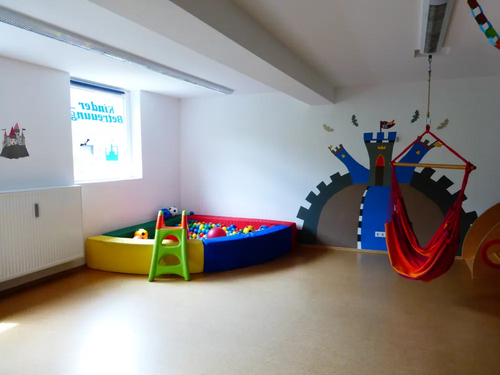 Bällebad in der Ecke des Bewegungsraums, dahinter eine Burg als Wandbild