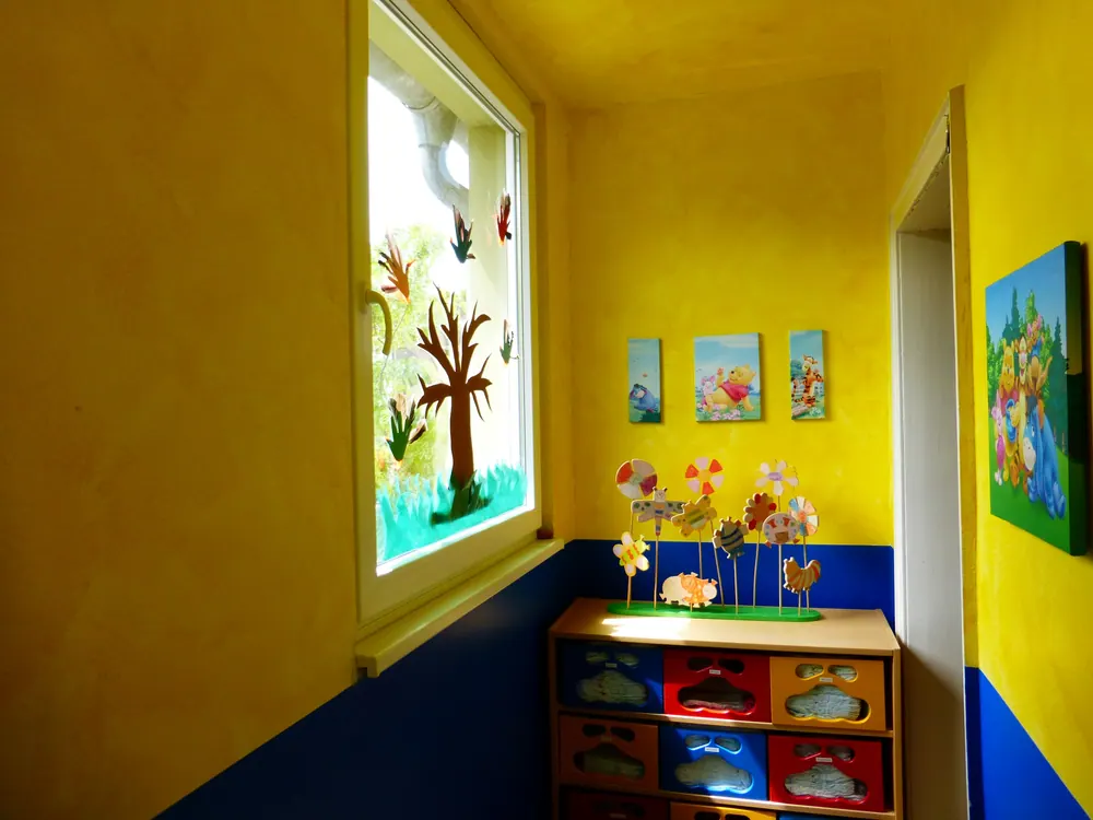 Gelb gestrichener Flur mit Fensterbild und Fächerschrank für die Kinder